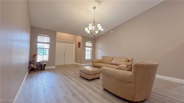 living room with an inviting chandelier, light hardwood / wood-style flooring, and vaulted ceiling