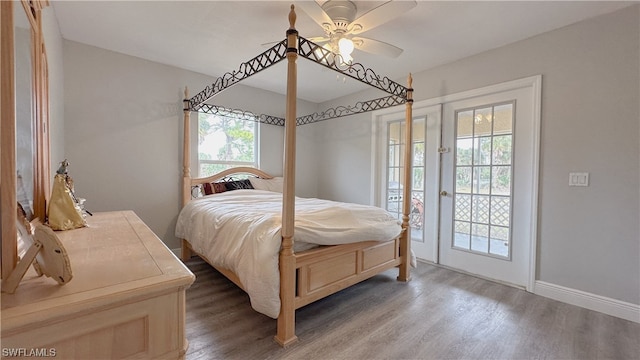 bedroom featuring ceiling fan, hardwood / wood-style floors, access to exterior, and multiple windows