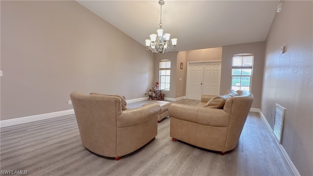 living room with wood-type flooring, a notable chandelier, high vaulted ceiling, and a healthy amount of sunlight