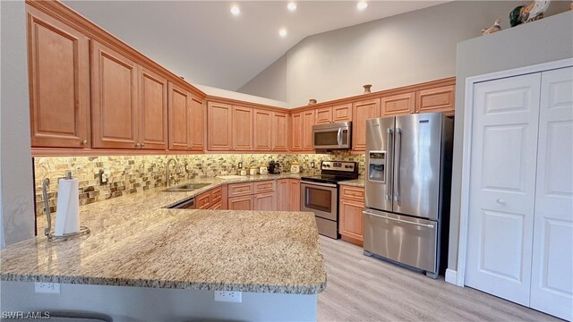 kitchen featuring high vaulted ceiling, kitchen peninsula, appliances with stainless steel finishes, and sink