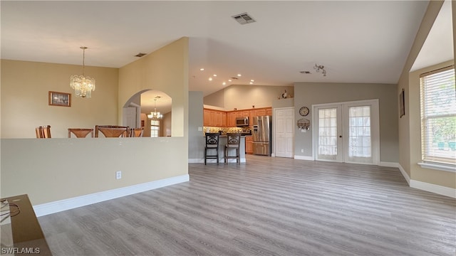 unfurnished living room with light hardwood / wood-style flooring, a chandelier, and vaulted ceiling