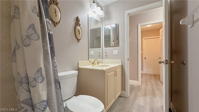 bathroom featuring wood-type flooring, vanity, and toilet