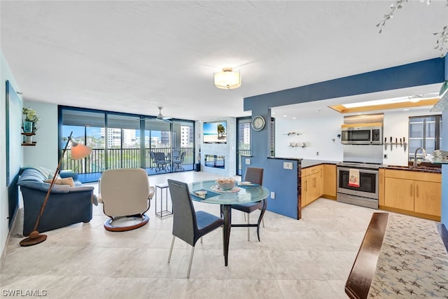 dining room featuring floor to ceiling windows, ceiling fan, and sink