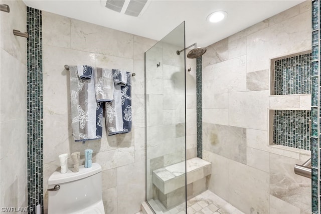 bathroom featuring tiled shower and toilet