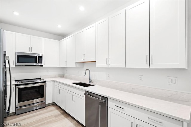 kitchen with light stone counters, white cabinetry, sink, and appliances with stainless steel finishes