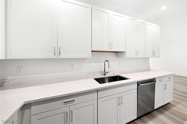 kitchen featuring dishwasher, sink, light wood-type flooring, light stone counters, and white cabinetry