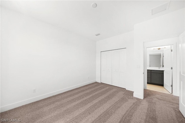 unfurnished bedroom with connected bathroom, light carpet, and a closet