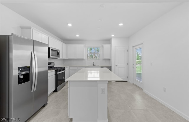 kitchen with a kitchen island, stainless steel appliances, light tile flooring, white cabinetry, and sink