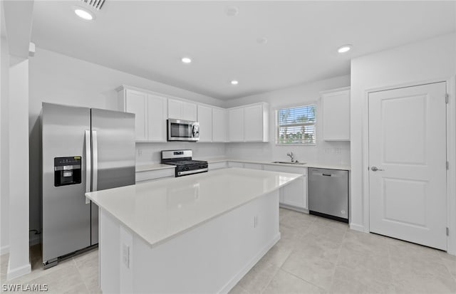 kitchen with a center island, appliances with stainless steel finishes, white cabinets, and light tile flooring