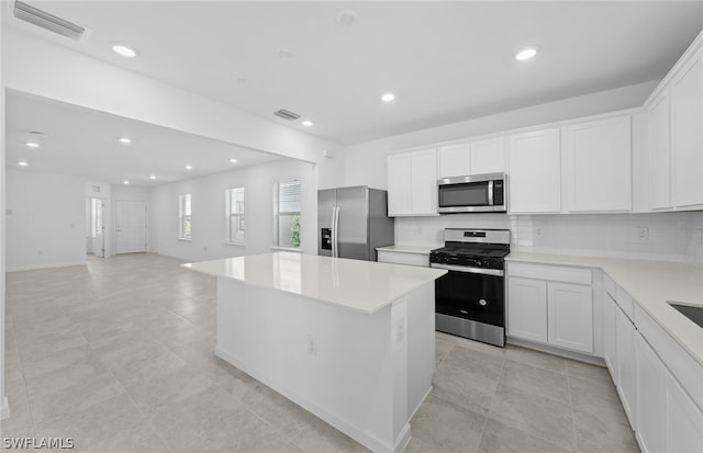 kitchen with tasteful backsplash, light tile floors, stainless steel appliances, and white cabinetry