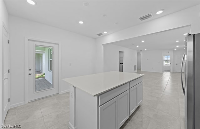 kitchen featuring stainless steel refrigerator, a center island, and light tile floors