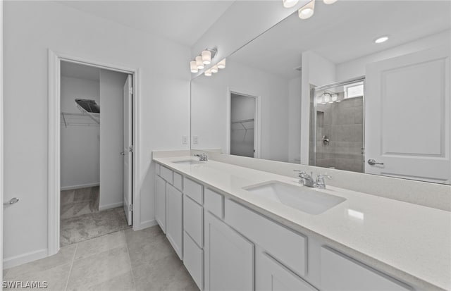 bathroom featuring vanity with extensive cabinet space, double sink, tiled shower, and tile floors