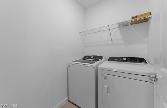 laundry area with light tile floors and washer and clothes dryer