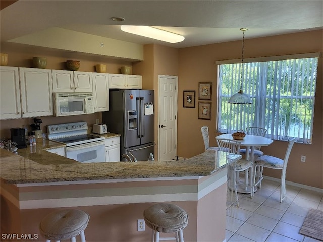 kitchen featuring white appliances, white cabinetry, decorative light fixtures, and light tile floors