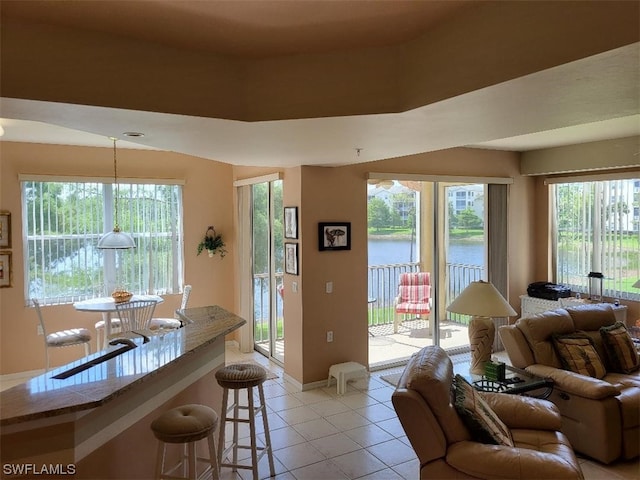 tiled living room featuring a water view and a tray ceiling