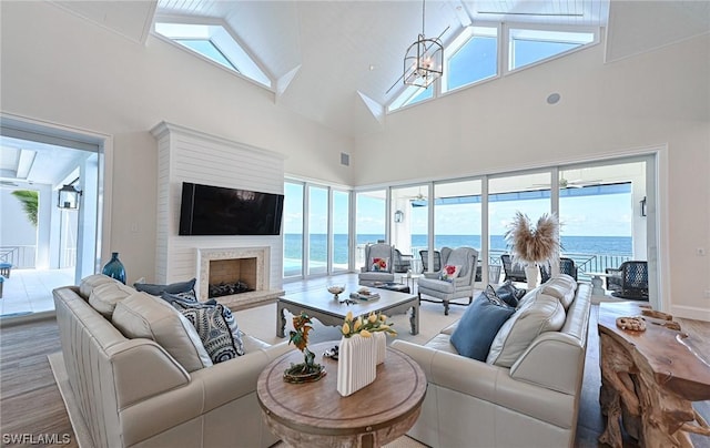 living room with a notable chandelier, high vaulted ceiling, and light hardwood / wood-style floors