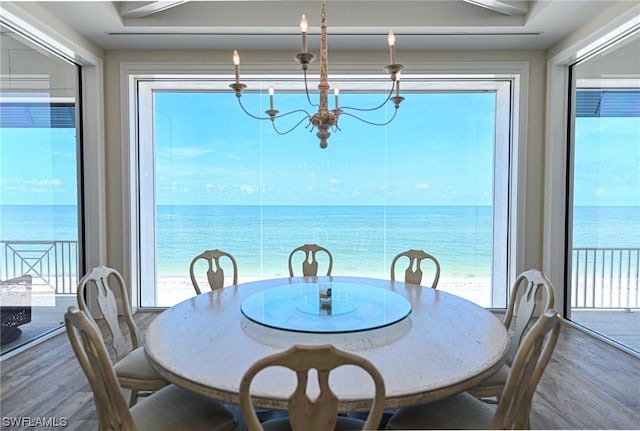 dining area with a water view, wood-type flooring, and a chandelier