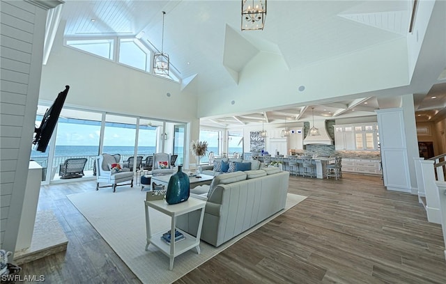 living room with beamed ceiling, wood-type flooring, high vaulted ceiling, and a chandelier