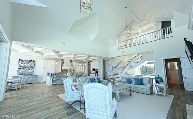 living room featuring beamed ceiling, wood-type flooring, high vaulted ceiling, and an inviting chandelier