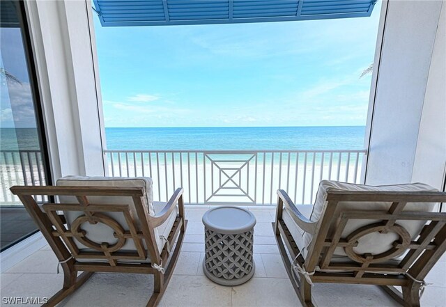 balcony featuring a water view and a beach view