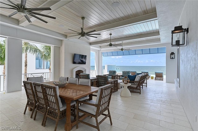 dining area featuring wood ceiling, a large fireplace, beam ceiling, and ceiling fan