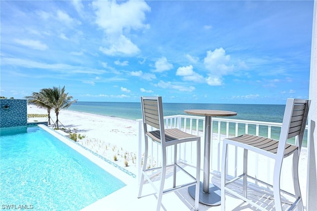 view of swimming pool with a water view and a beach view