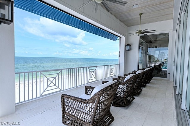 view of patio with a beach view, ceiling fan, and a water view