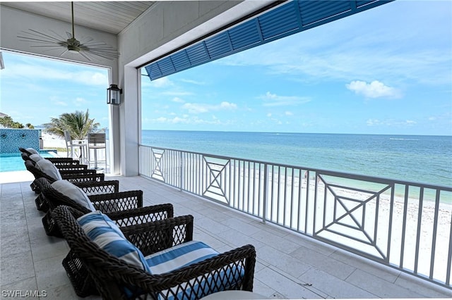 balcony with a water view, ceiling fan, and a beach view