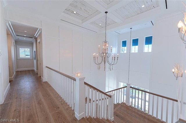 hallway with coffered ceiling, a notable chandelier, beam ceiling, and hardwood / wood-style floors