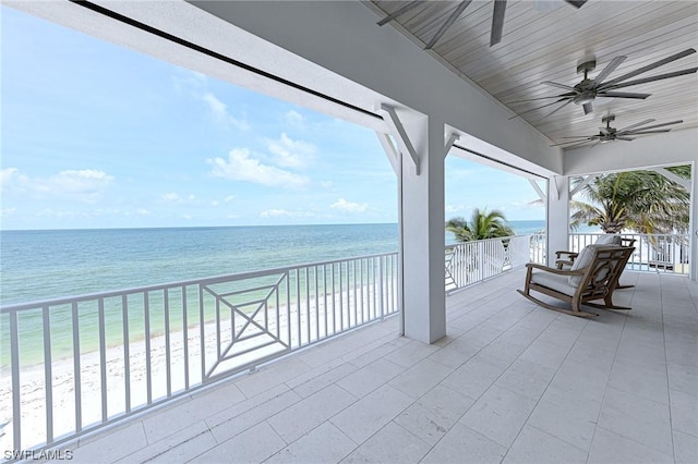 view of patio with a water view, ceiling fan, a beach view, and a balcony