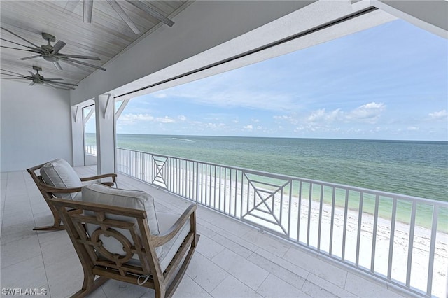 balcony featuring a water view, a beach view, and ceiling fan