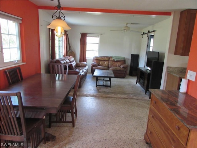 dining space featuring ceiling fan and a barn door