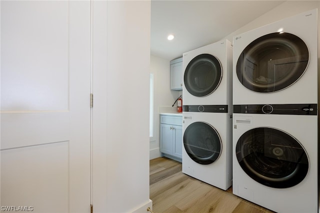 washroom with stacked washer / dryer, cabinets, washer and clothes dryer, and light wood-type flooring