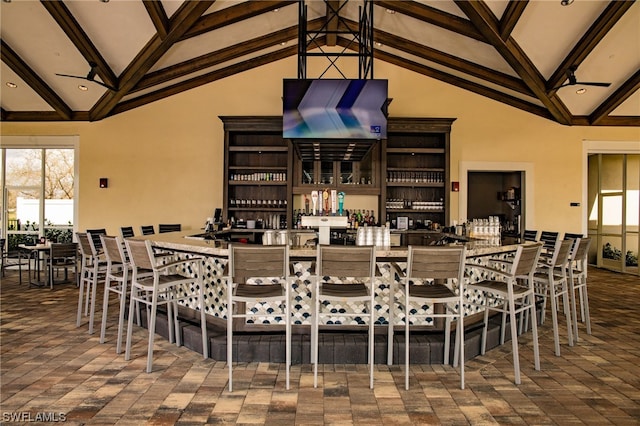 tiled dining area with bar area, high vaulted ceiling, and beamed ceiling