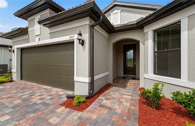 entrance to property featuring central air condition unit and a garage