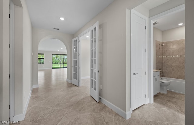 corridor with french doors and light tile flooring