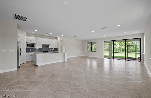 unfurnished living room featuring light tile floors and sink