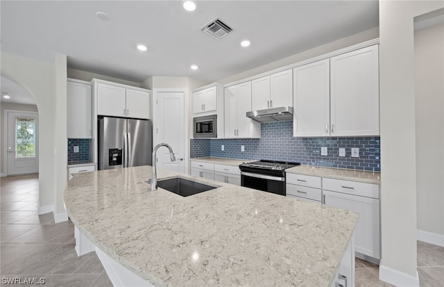 kitchen with stainless steel appliances, tasteful backsplash, a center island with sink, white cabinets, and sink