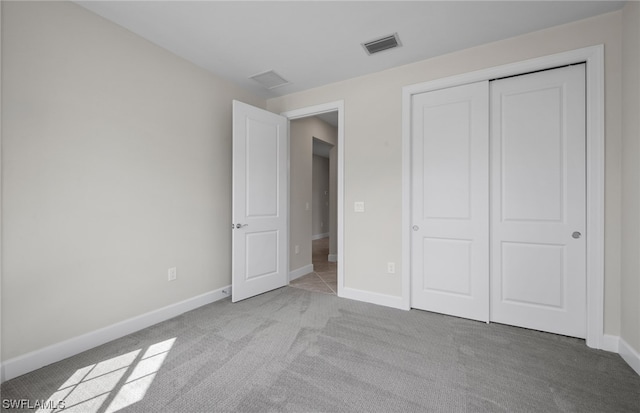 unfurnished bedroom featuring a closet and light colored carpet