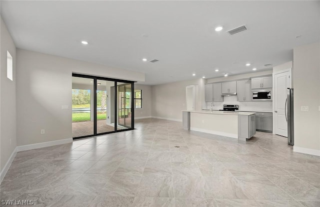 kitchen featuring gray cabinets, a center island with sink, stainless steel appliances, and sink