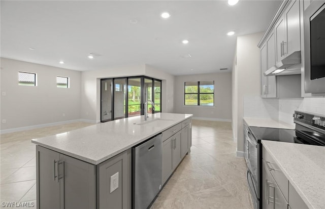 kitchen with gray cabinetry, light stone counters, sink, and appliances with stainless steel finishes