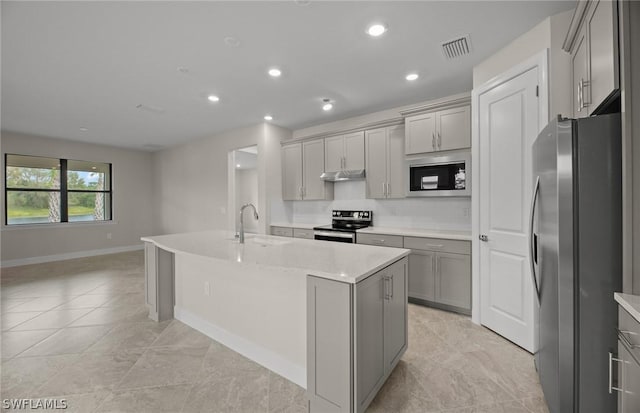 kitchen featuring gray cabinetry, sink, a kitchen island with sink, light tile patterned flooring, and appliances with stainless steel finishes