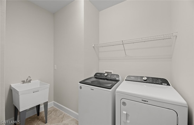 washroom featuring light tile patterned floors, washing machine and dryer, and sink