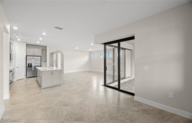 kitchen featuring plenty of natural light, stainless steel appliances, and an island with sink