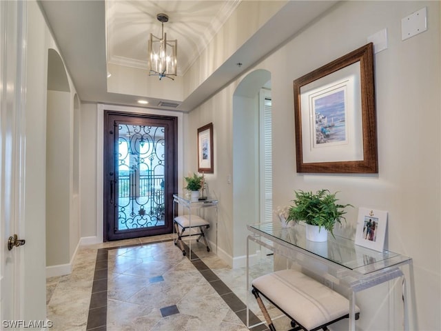 foyer with crown molding and a notable chandelier