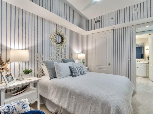 bedroom featuring ceiling fan, sink, connected bathroom, and light colored carpet