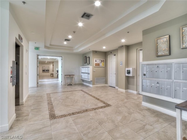 corridor with a raised ceiling and a mail area