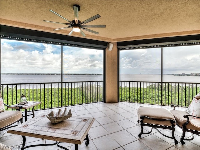 sunroom / solarium featuring a water view and ceiling fan