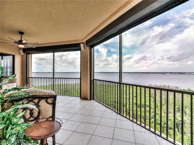 sunroom / solarium featuring ceiling fan and a water view