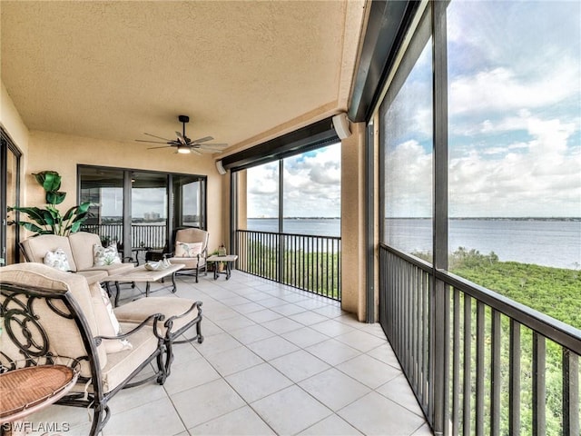 sunroom / solarium with ceiling fan and a water view